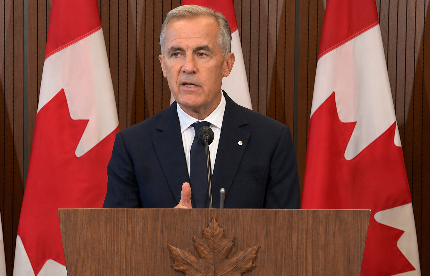 Mark Carney prononce un discours devant plusieurs drapeaux canadiens.