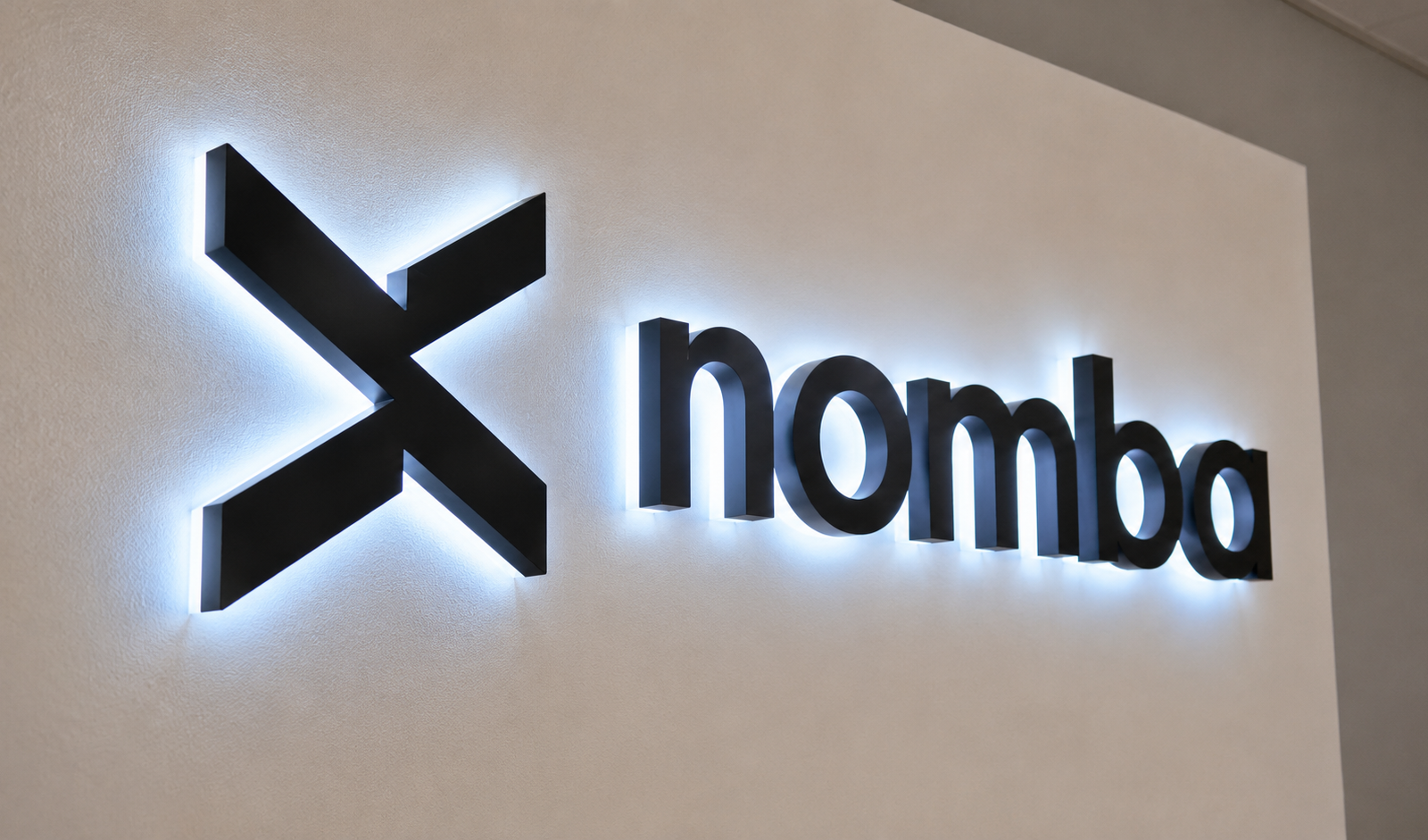 Logo lumineux de la fintech nigériane Nomba sur un mur.